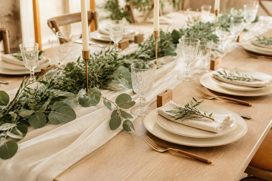 Décoration de table de mariage élégante avec chemin de table en feuillage, bougies et vaisselle raffinée dans une salle de réception lumineuse